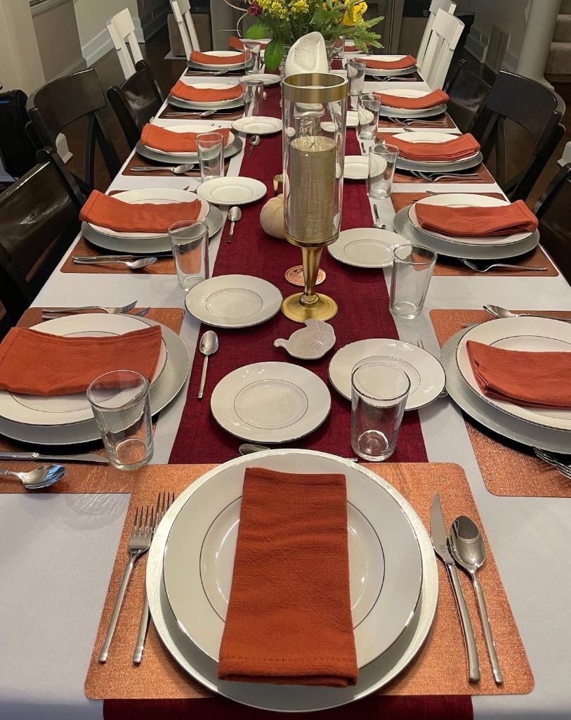Formal table setting with orange napkins and burgundy runner