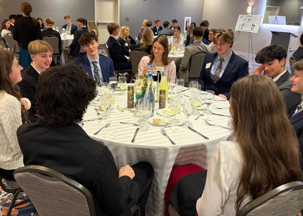 Young adults at a formal dining etiquette class in a ballroom