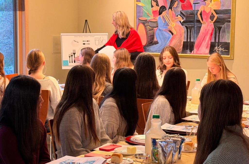 Instructor teaching dining etiquette to a group of girls